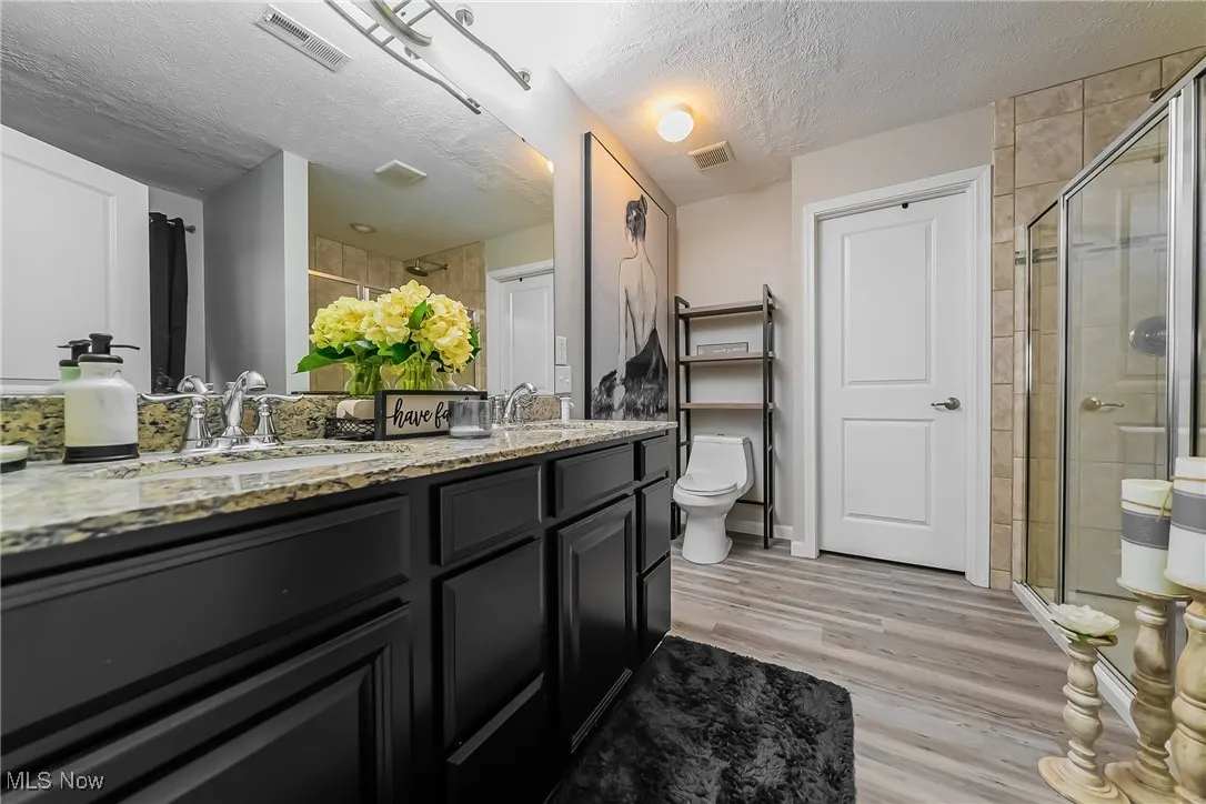 Full bath with a stall shower, visible vents, and a textured ceiling