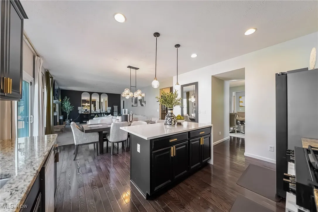 Kitchen featuring open floor plan, dark wood-type flooring, freestanding refrigerator, pendant lighting, and recessed lighting