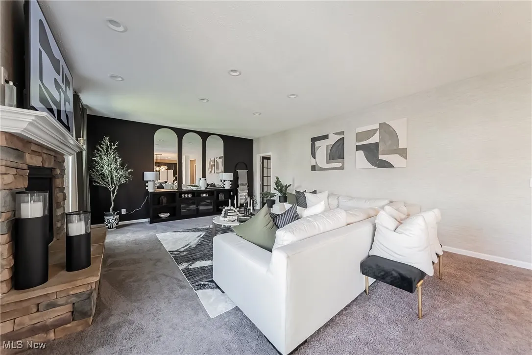 Living area with carpet, baseboards, a stone fireplace, and recessed lighting