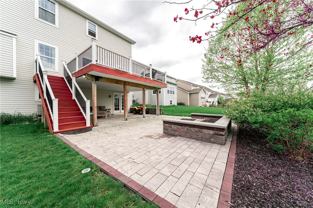 Rear view of property featuring a patio, a deck, a lawn, french doors, and stairway