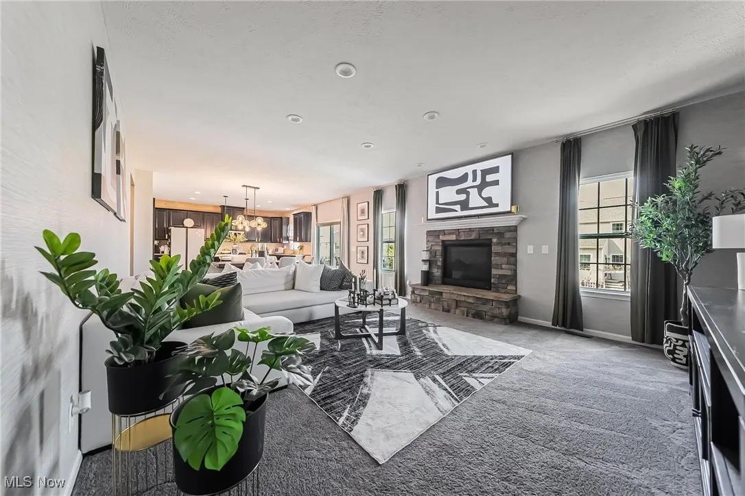 Living area with carpet flooring, baseboards, a stone fireplace, and recessed lighting