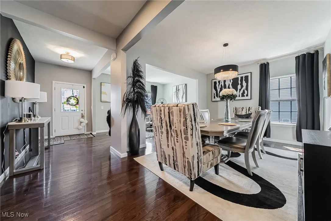 Dining room with baseboards, an inviting chandelier, and hardwood / wood-style flooring