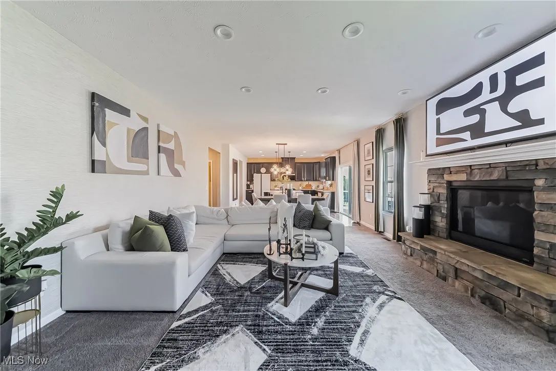 Carpeted living area featuring a chandelier, a stone fireplace, and recessed lighting