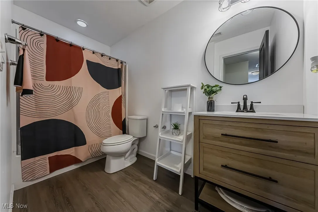 Full bath featuring toilet, vanity, a shower with shower curtain, and wood finished floors