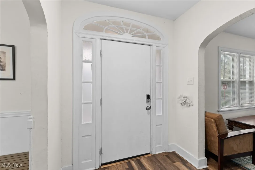 Foyer with arched walkways, dark wood-style floors, and baseboards