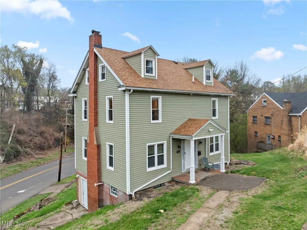 View of front of home featuring driveway, a front yard, a porch, a shingled roof, and a chimney