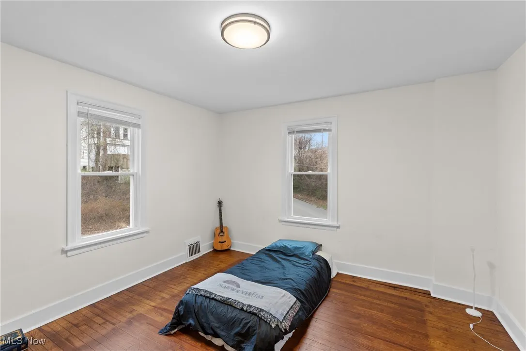 Bedroom with baseboards, multiple windows, and hardwood / wood-style flooring