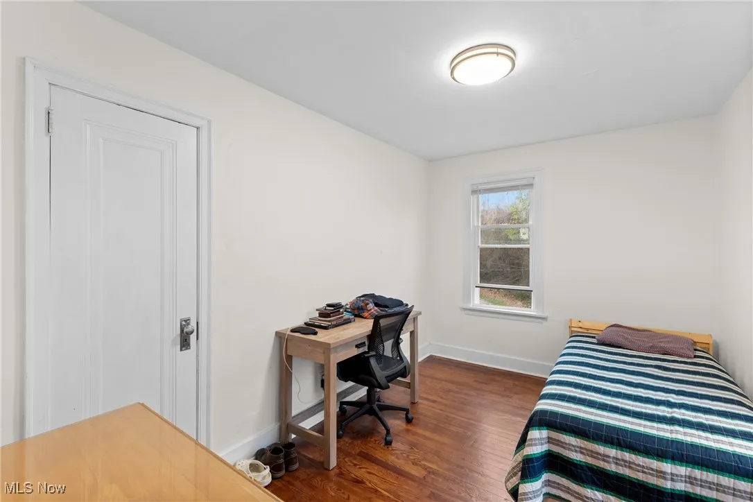 Bedroom with dark wood-type flooring and baseboards
