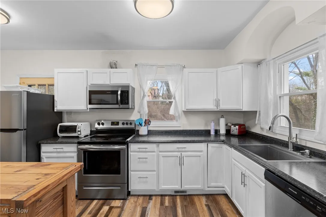 Kitchen with white cabinetry, a sink, stainless steel appliances, and a toaster