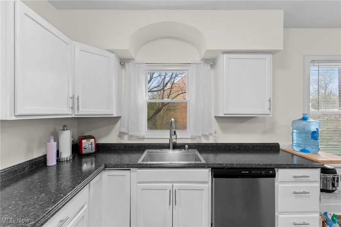 Kitchen featuring white cabinets, a sink, and dishwasher