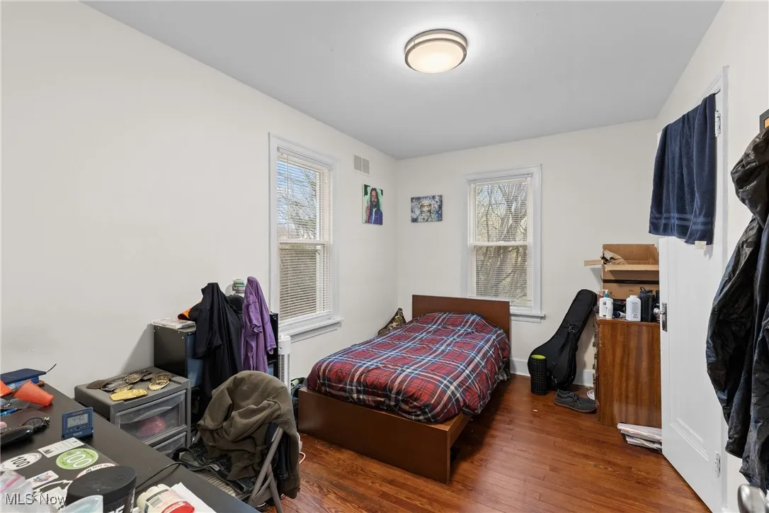 Bedroom with baseboards, visible vents, wood finished floors, and multiple windows