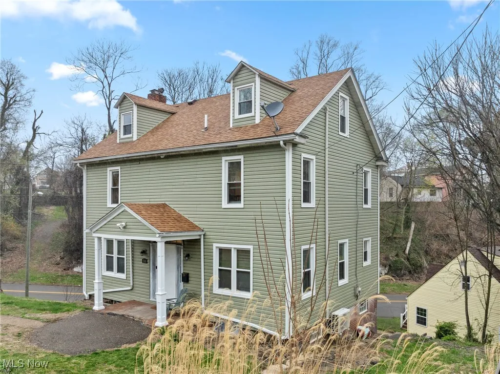 View of front of property featuring a chimney and a shingled roof