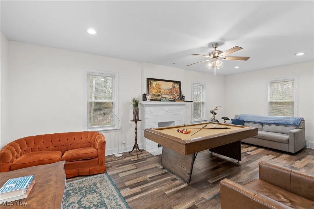 Recreation room with recessed lighting, ceiling fan, a brick fireplace, pool table, and wood finished floors