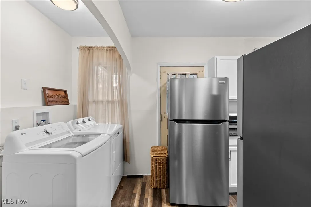 Laundry area featuring dark wood-style flooring, arched walkways, washer and clothes dryer, and laundry area