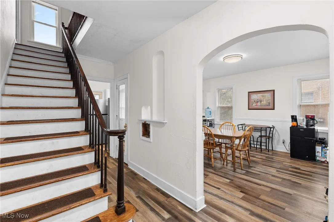 Staircase featuring baseboards, wood finished floors, and arched walkways