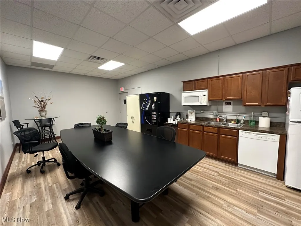Office area featuring a sink, light wood-style floors, visible vents, and a paneled ceiling
