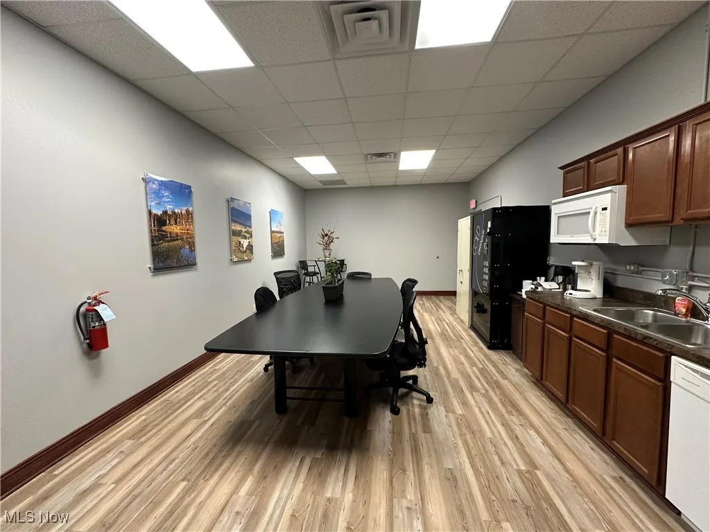 Office area with baseboards, visible vents, light wood-style flooring, and a sink