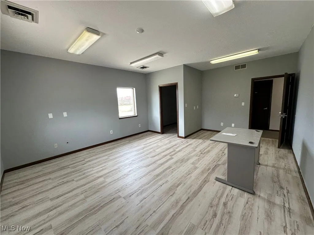 Empty room with baseboards, visible vents, and light wood-type flooring