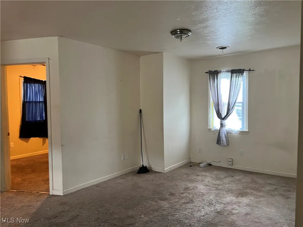 Carpeted spare room with baseboards and a textured ceiling