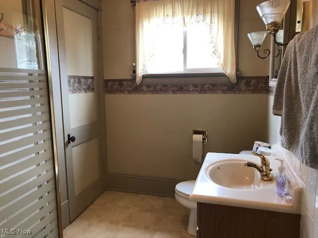 Bathroom featuring vanity, toilet, and a wainscoted wall