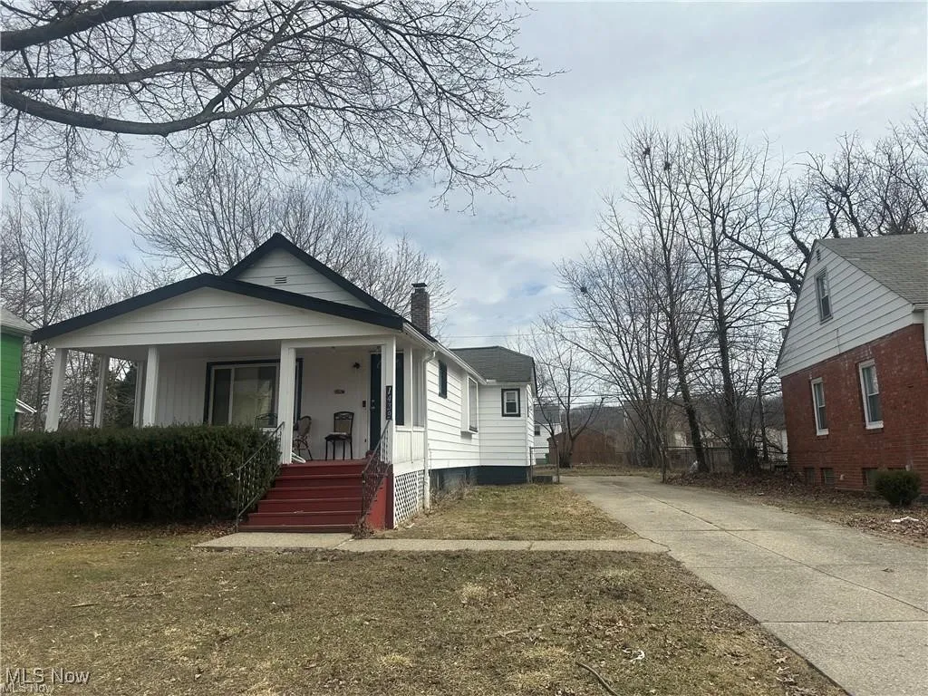 Bungalow-style house featuring covered porch, driveway, and a chimney