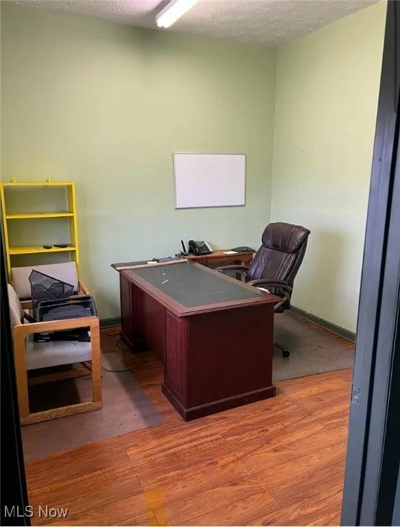 Office area with wood finished floors, baseboards, and a textured ceiling