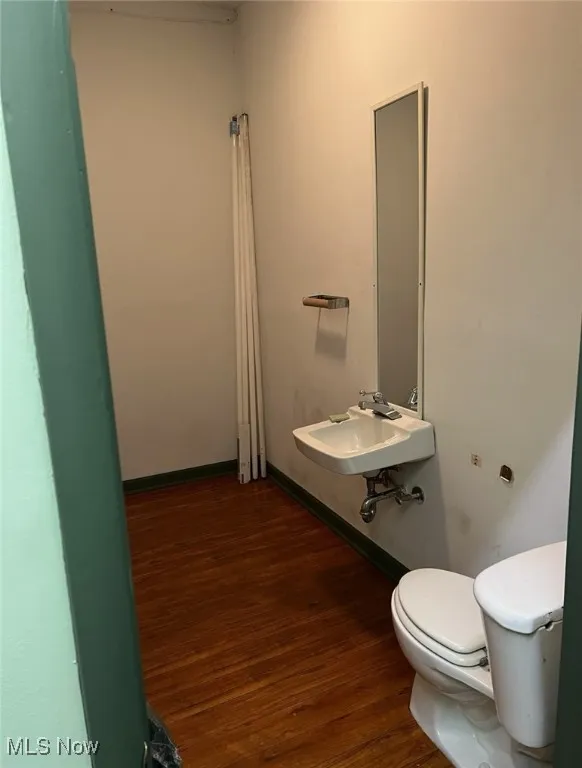 Bathroom featuring a sink, baseboards, toilet, and wood finished floors