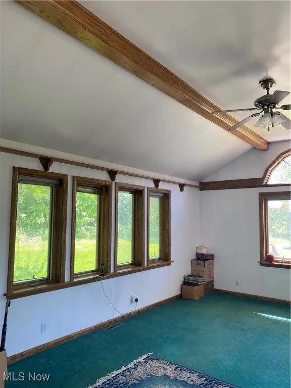 Carpeted empty room featuring ceiling fan and baseboards