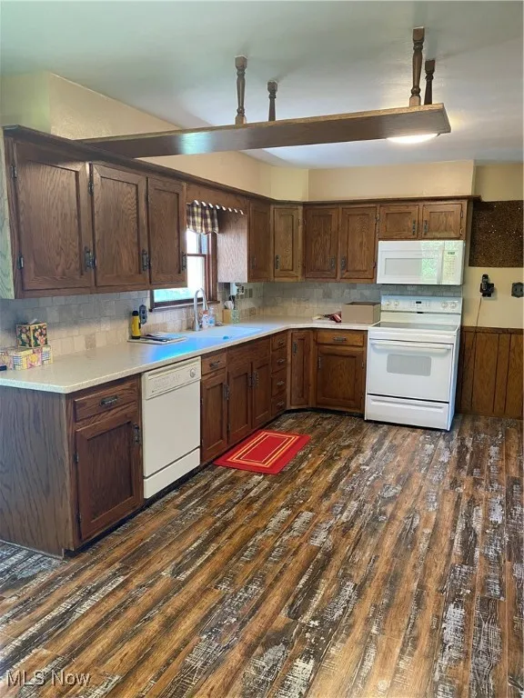 Kitchen featuring dishwashing machine, range, dark wood-style flooring, and light countertops