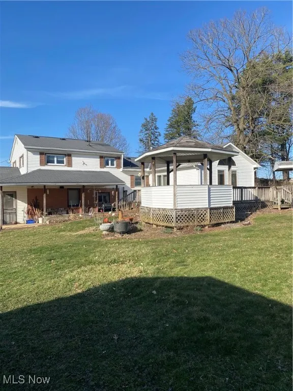 Rear view of house featuring a gazebo, a yard, and a wooden deck
