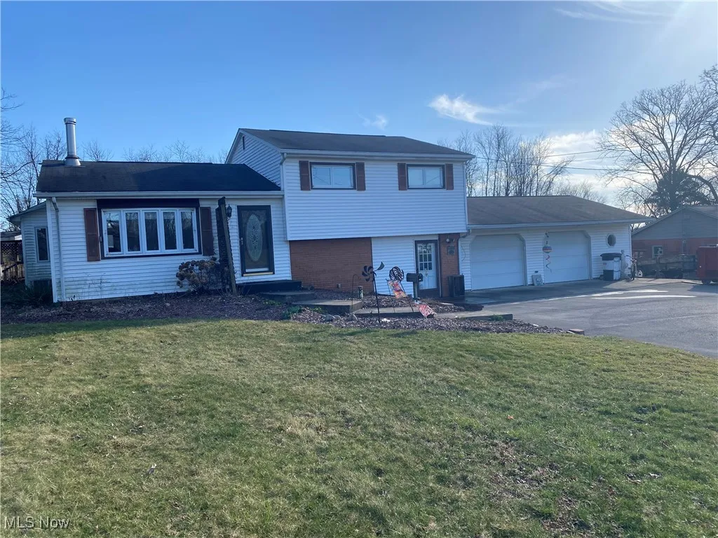 Tri-level home with brick siding, aphalt driveway, a front yard, and an attached garage