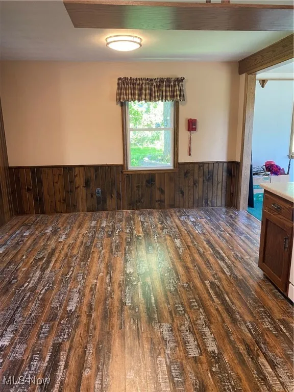 Unfurnished room featuring wood-type flooring, wainscoting, and wooden walls