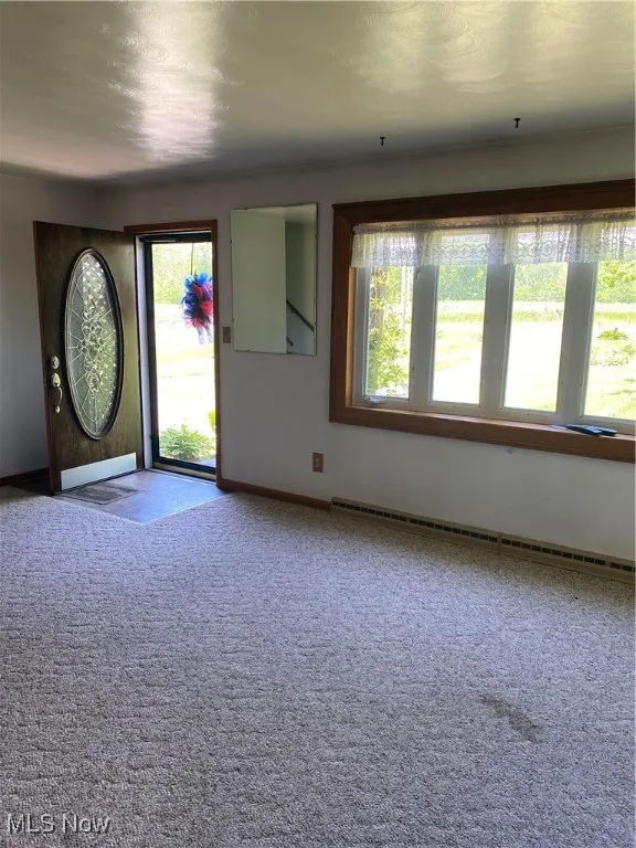 Carpeted entrance foyer with a baseboard heating unit, healthy amount of natural light, and baseboards
