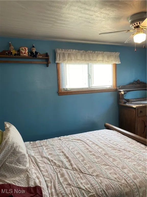 Bedroom featuring a ceiling fan and a textured ceiling