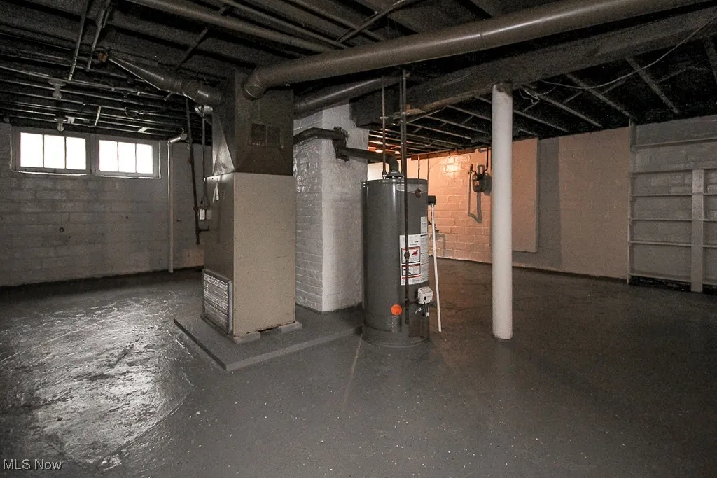 Basement with gas water heater, concrete block wall, and heating unit