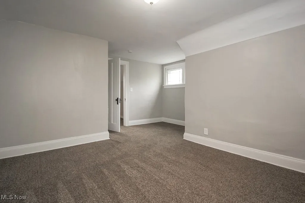 Empty room with baseboards and dark carpet