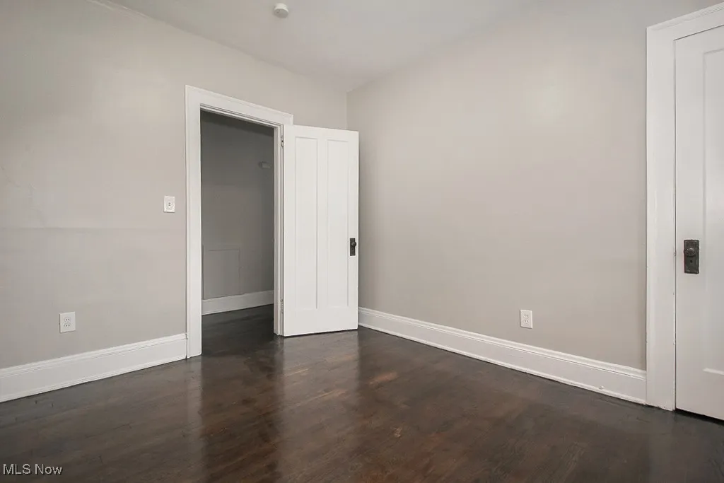 Empty room featuring baseboards and dark wood-type flooring