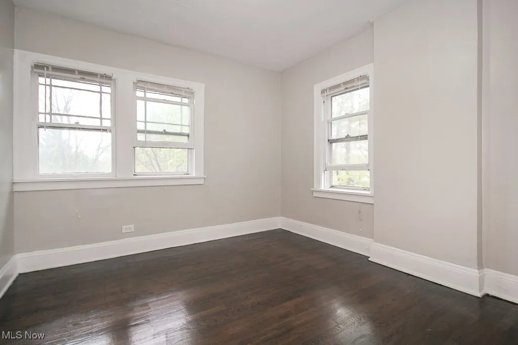 Spare room featuring dark wood-style floors and baseboards