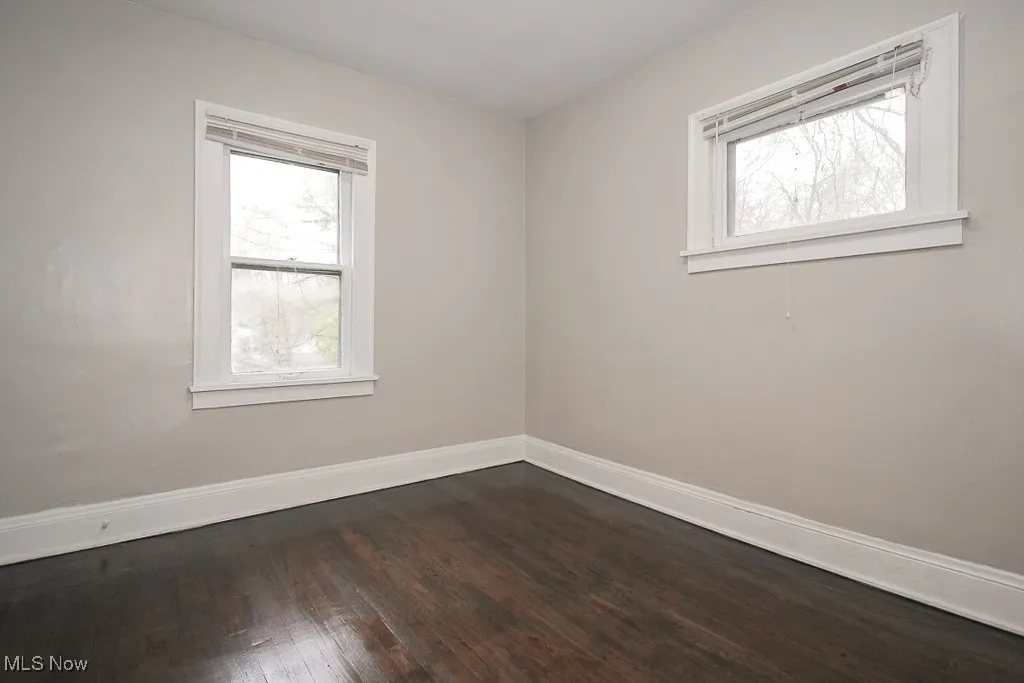 Unfurnished room with dark wood finished floors and baseboards