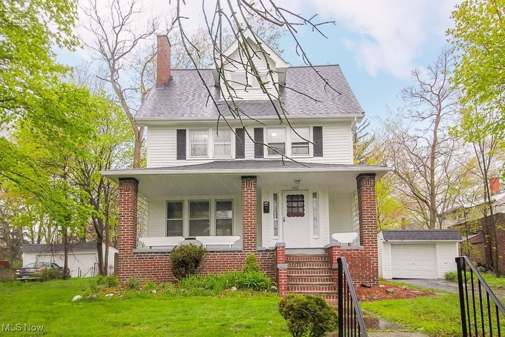 Traditional style home featuring a porch, a front yard, an outdoor structure, and a chimney