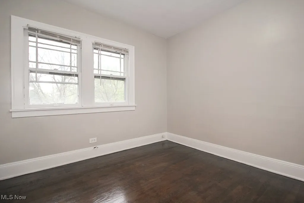 Empty room featuring dark wood-type flooring and baseboards