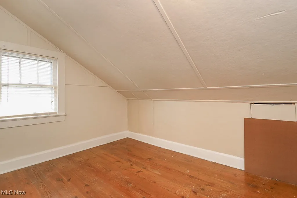 Additional living space with baseboards, lofted ceiling, and hardwood / wood-style floors