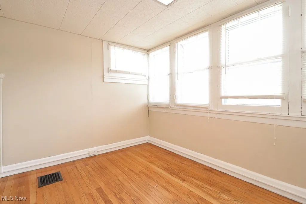 Empty room featuring visible vents, baseboards, and light wood-style floors