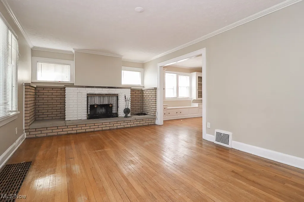 Unfurnished living room with hardwood / wood-style flooring, baseboards, and visible vents