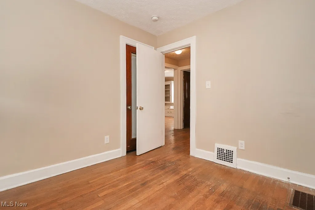 Spare room featuring baseboards, visible vents, and wood-type flooring