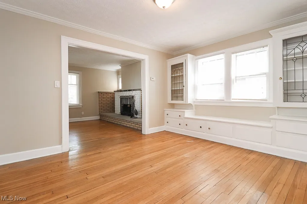 Unfurnished living room with light wood-style flooring, a fireplace, and ornamental molding
