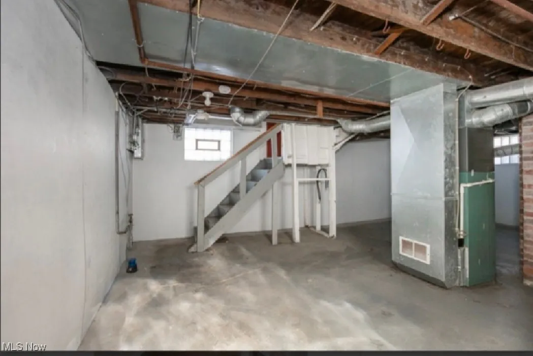 Below grade area featuring heating unit, visible vents, and stairs