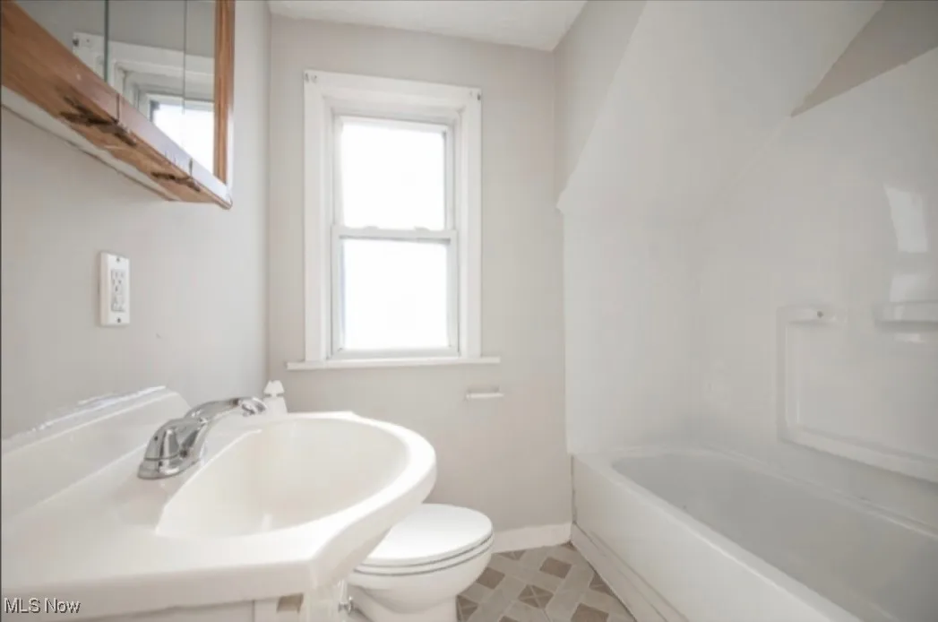 Bathroom featuring a sink, baseboards, and toilet