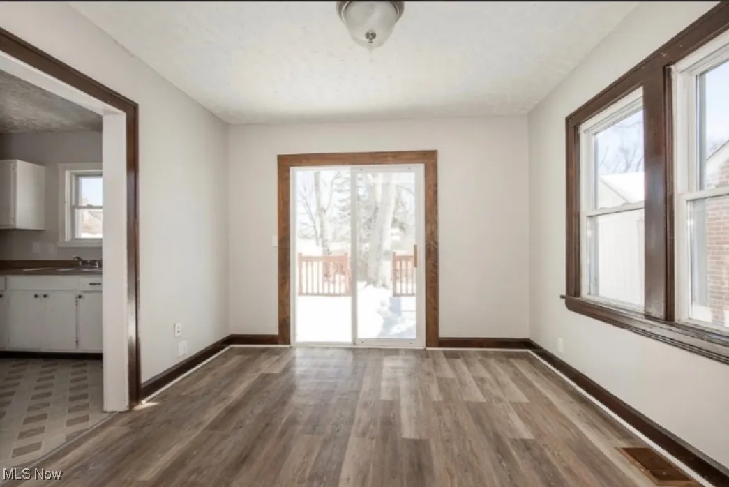 Unfurnished dining area with a sink, baseboards, a textured ceiling, and wood finished floors
