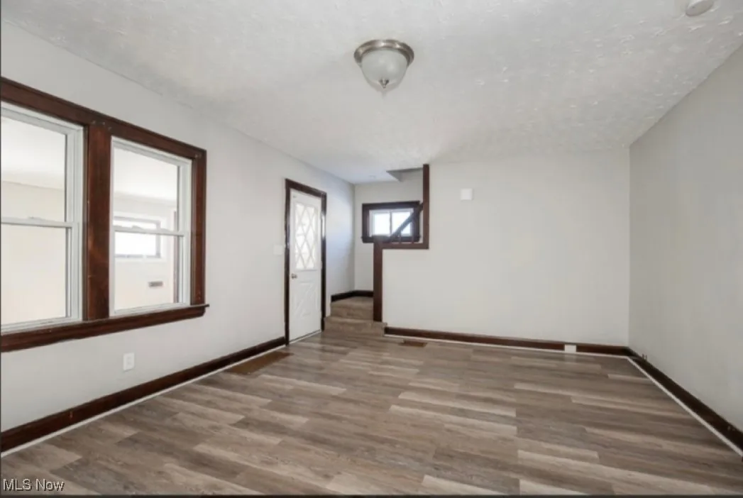 Unfurnished room featuring wood finished floors, baseboards, and a textured ceiling